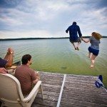 engaged couple jumping in pickerel lake northern MI photo